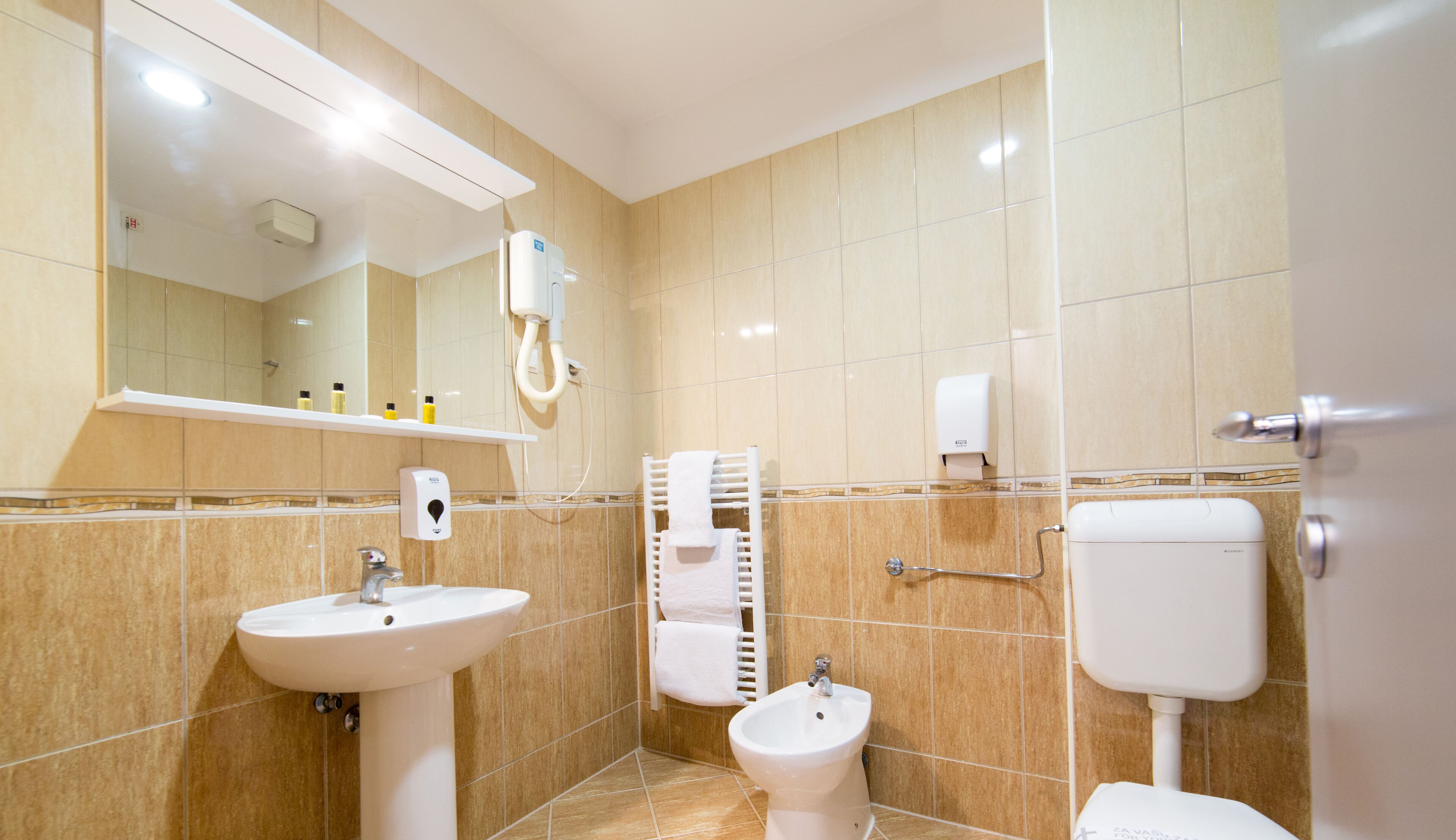 Une salle de bain moderne équipée d’un lavabo, d’un bidet et de toilettes.