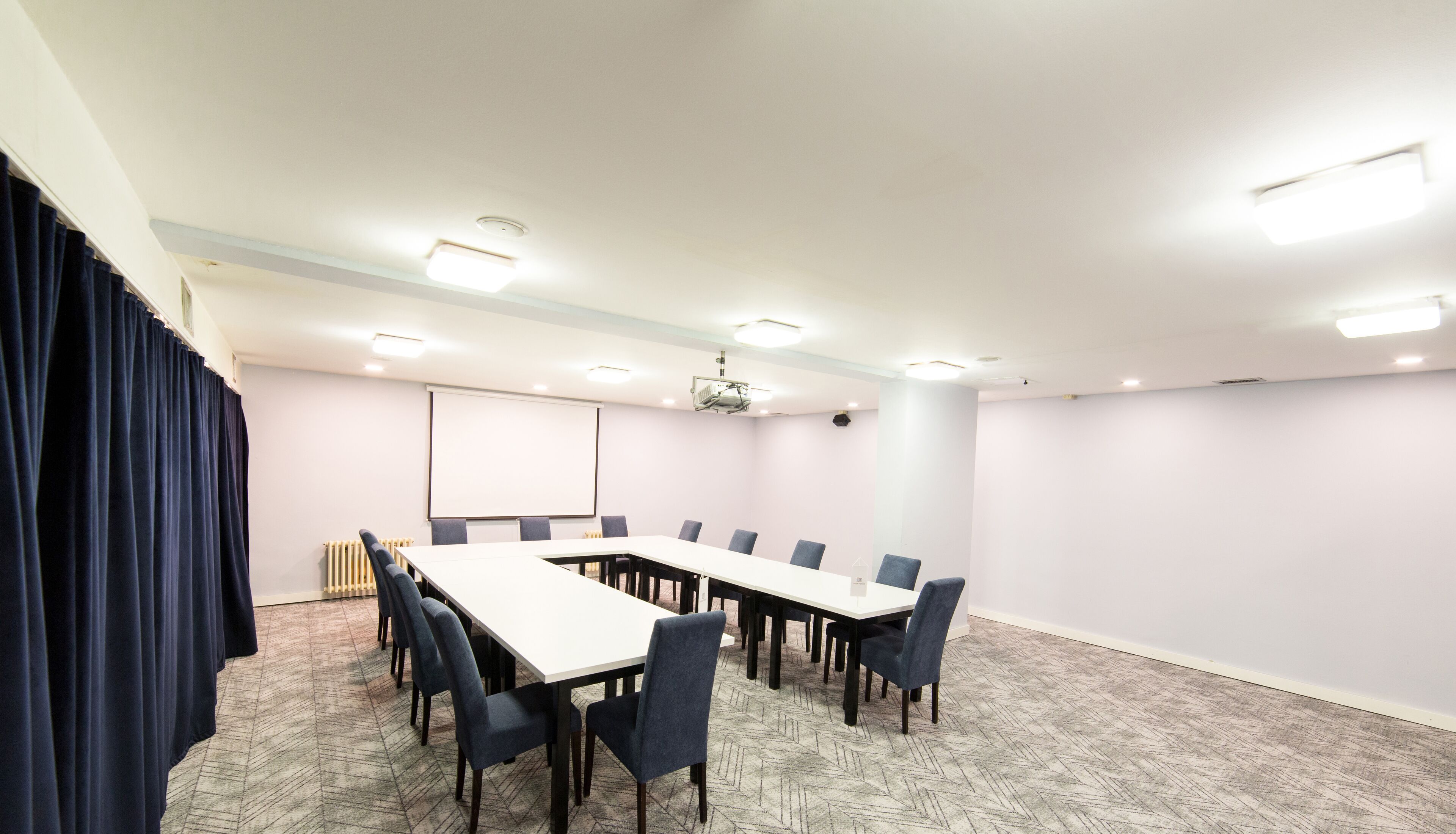 A conference room with a long table, chairs, a projector, and a screen.