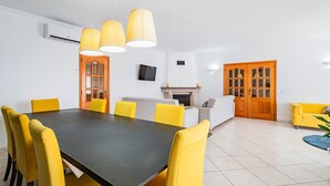 A dining area with a black table and yellow chairs, a fireplace, and wooden doors. - Villa Coelha - Table tennis and Pool Table (Guia)