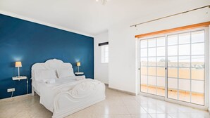 A bedroom with a bed, two bedside lamps, a window, and a view of the outside. - Villa Coelha - Table tennis and Pool Table (Guia)