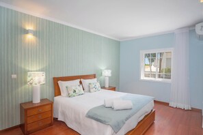 A neatly arranged bedroom with a bed, bedside tables, and a window with curtains.