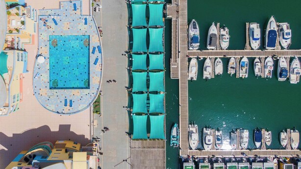 An aerial view of a marina with boats docked, a swimming pool, and a covered walkway. - Al Marina View Uma - Lux ground floor apartment on the marina (Albufeira)