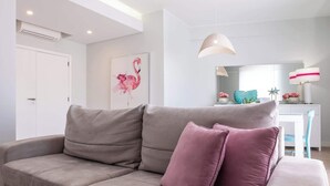 A modern living room with a sofa, a glass coffee table, and a dining area with a chair and a table. - Al Marina View Uma - Lux ground floor apartment on the marina (Albufeira)