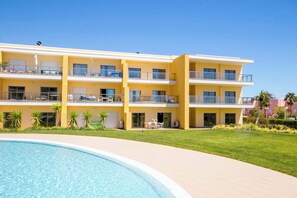 A multi-story hotel with a pool, balconies, and a well-maintained lawn.