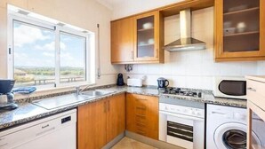 Una cucina moderna con mobili in legno, forno a incasso, lavatrice e una finestra vista.