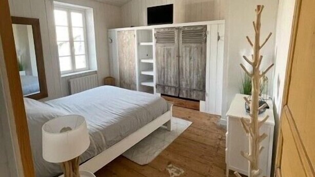 A bedroom with a bed, a bedside table, a wardrobe, and a mirror. - House in the center, near the beach (Rivedoux-Plage)