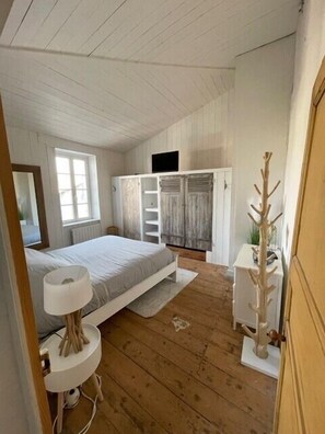 Een slaapkamer met een bed, nachtkastje, kledingkast en spiegel.