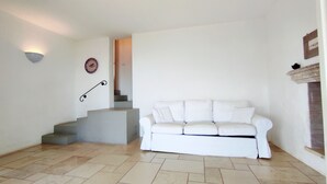 A white sofa, a staircase, and a wall-mounted clock in a room with tiled flooring. - Villa Marinus- Private Pool And Breathtaking Sea View (Corsano)