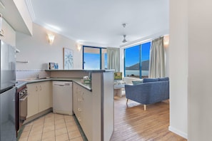 A modern kitchen with a built-in dishwasher, a dining area with a view, and a seating area with a blue sofa.