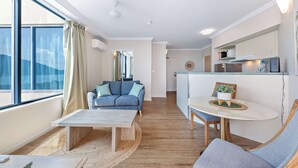 En moderne stue med sofa, sofabord og et spiseområde med et lille bord og stole.