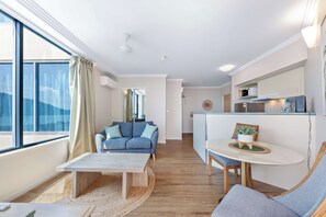 A modern living room with a sofa, coffee table, and a dining area with a small table and chairs.