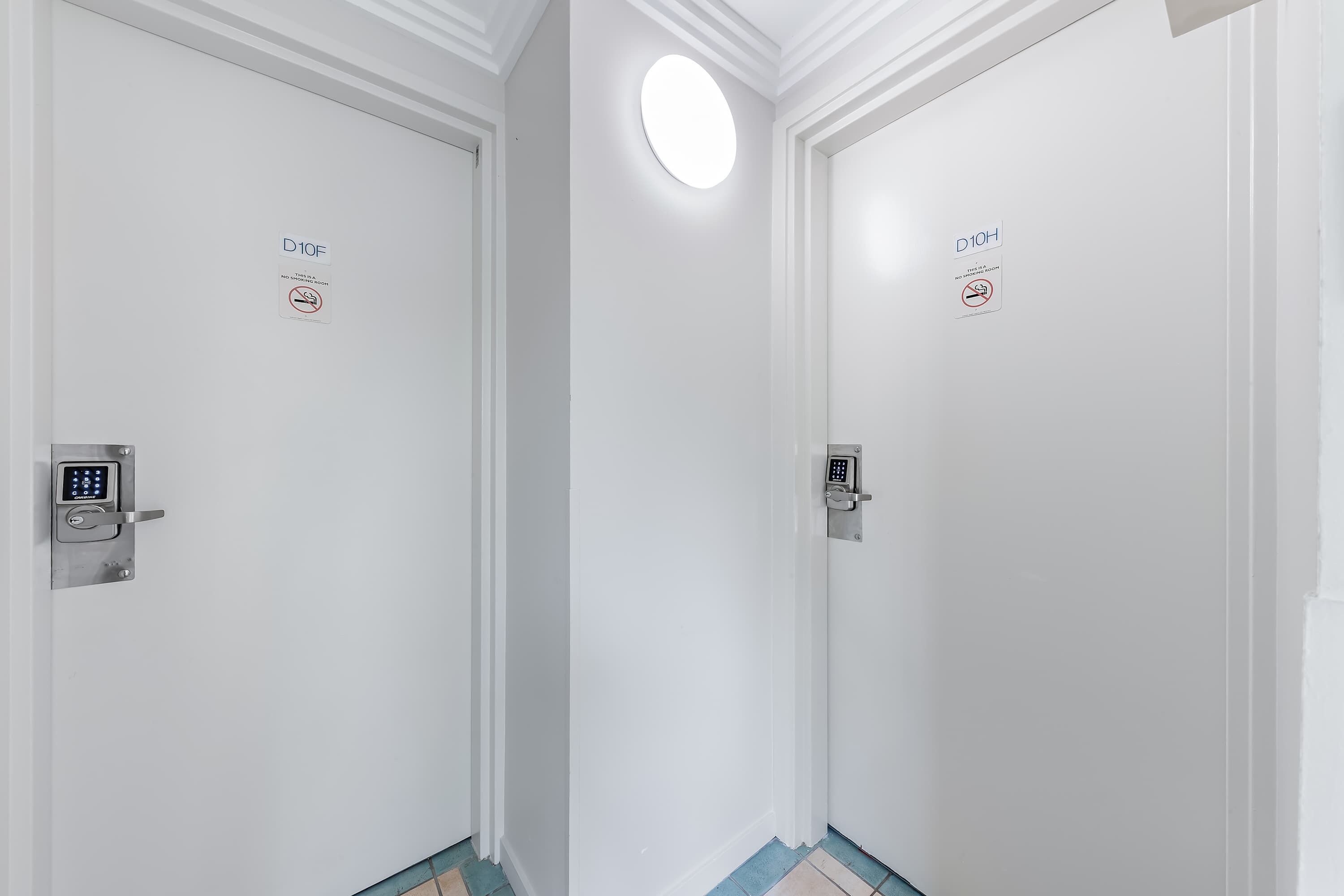 A hallway with two doors, each with a no-smoking sign and a digital lock.