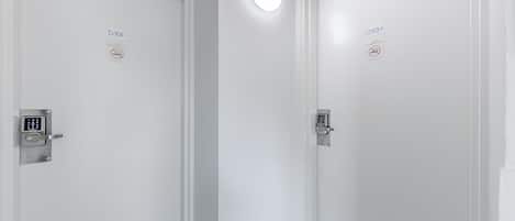 A hallway with two doors, each with a no-smoking sign and a digital lock.