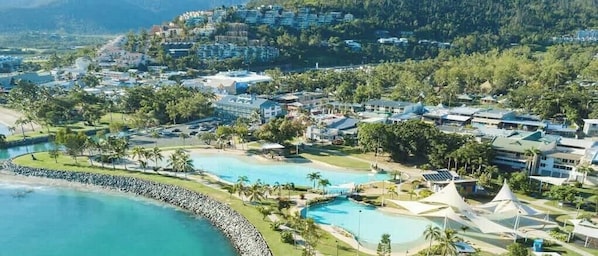 A resort with multiple swimming pools, a beach, and a mountainous backdrop.