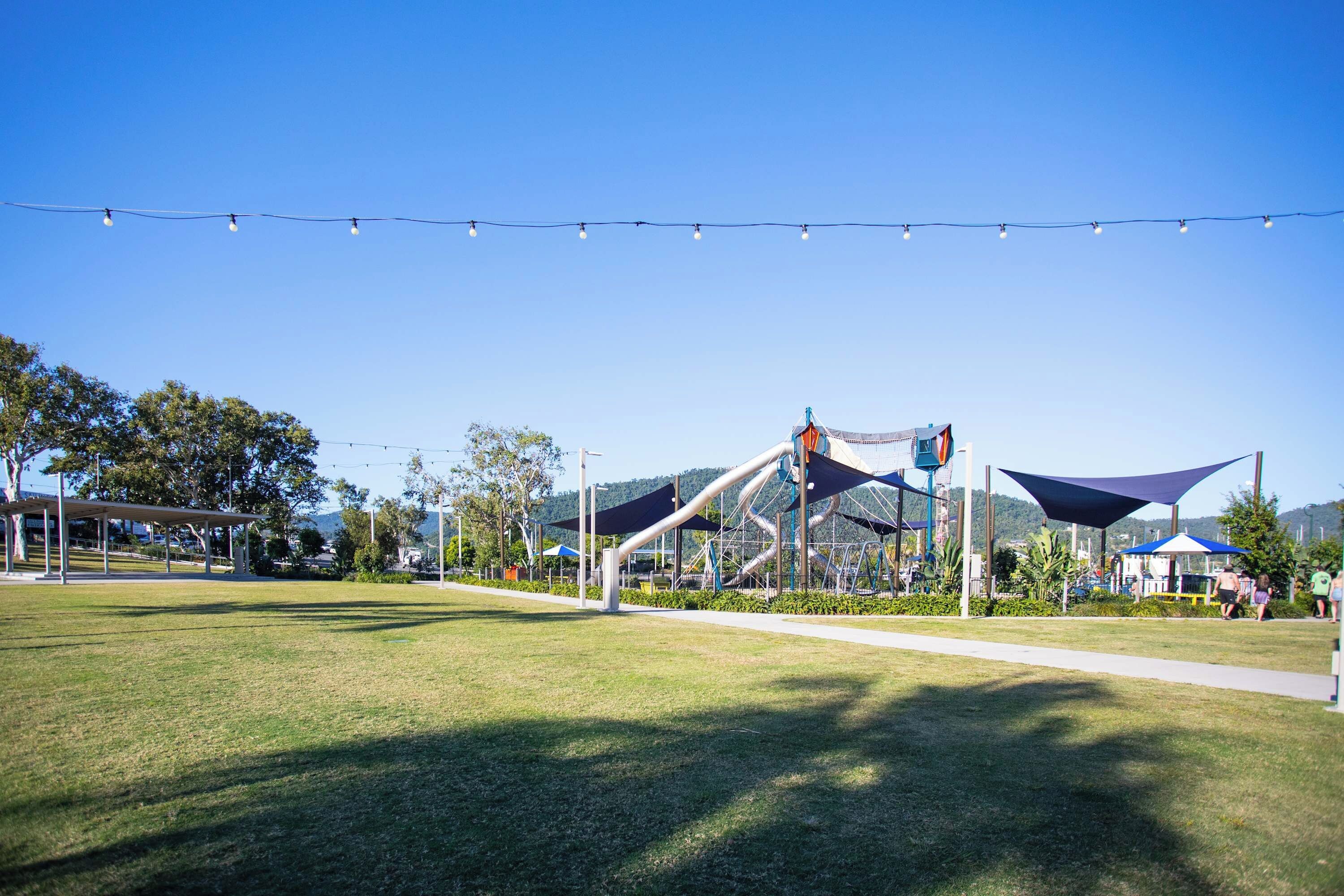 A park with a playground, picnic areas, and a clear sky.