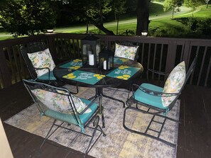A patio with a round table and four chairs, each with a cushion featuring a lemon design. - Log Cabin on Main St. In the ❤️ of Winston Salem. Sleeps 4 comfortably.  (Winston-Salem)