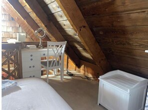 A small attic bedroom with a wooden ceiling, a white desk with a mirror, a white chair, a bed, and a white dresser. - Log Cabin on Main St. In the ❤️ of Winston Salem. Sleeps 4 comfortably.  (Winston-Salem)