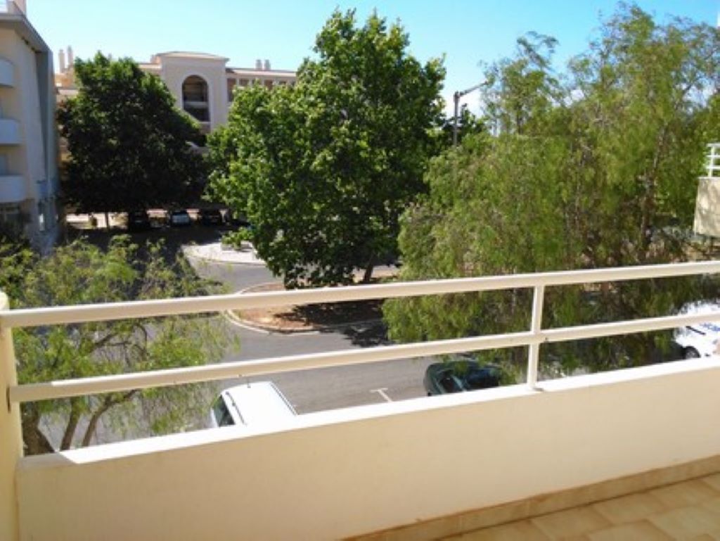 A balcony with a view of a street and trees.