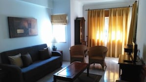 A living room with a sofa, armchairs, a coffee table, and a television. - Finfoot Black Apartment, Vilamoura, Algarve (Quarteira)