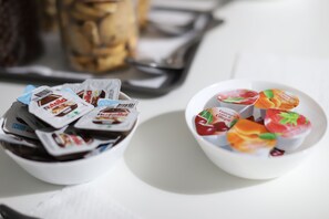 Two bowls of packaged food items, one with chocolate and the other with fruit-flavored yogurts, on a white surface.