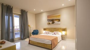 Habitación de hotel moderna con una cama grande, un escritorio y una silla. Tiene un balcón con cortinas, un cuadro en la pared y una ventana con persianas.