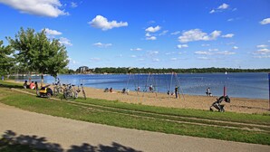 Un parco con una spiaggia sabbiosa, un lago e un cielo azzurro intenso.