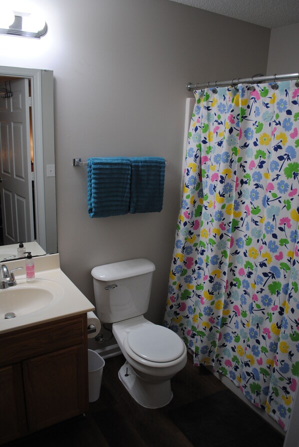 A bathroom with a toilet, sink, and blue towels hanging on the wall.