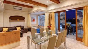 Amplia sala de estar con mesa de comedor de vidrio, asientos cómodos y vistas al patio exterior.