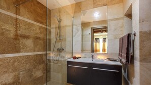 Un baño moderno con ducha envuelta en vidrio, tocador con espejo y perchero para toallas.