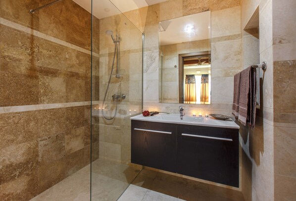 Une salle de bain moderne avec une douche à parois de verre, un meuble-lavabo avec un miroir et un porte-serviettes.