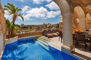 A rooftop pool with lounge chairs and a stone wall. - Private Villa with Indoor Heated Jacuzzi (L-Gharb)