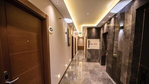 A hallway with wooden doors, marble flooring, and recessed lighting. - Ozkaya Otel (Sivas)