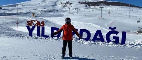 Una persona con una chaqueta roja de pie frente a un cartel que dice "Sivas Yildagi".