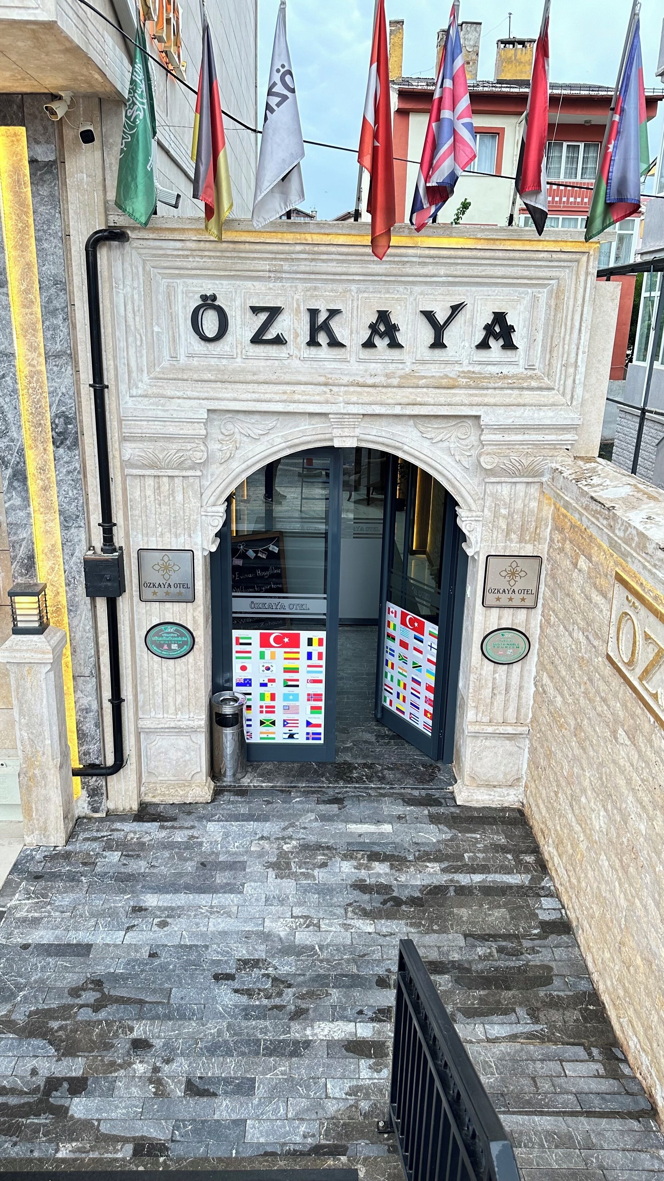 De ingang van Hotel Ozkaya met een stenen gevel, een naamplaatje en meerdere vlaggen.