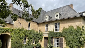 Ein historisches Steinhaus mit efeuüberwucherten Mauern, einem Innenhof mit Kübelpflanzen und traditioneller europäischer Architektur.