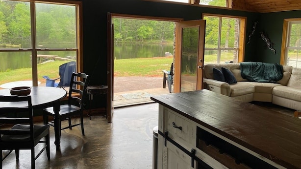 L’intérieur chaleureux d’un chalet comprend un coin repas, une cuisine et un espace détente avec vue sur un lac.