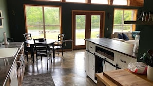 Une cuisine avec un coin repas, de grandes fenêtres et une vue sur un lac.
