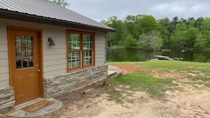 Une maison avec des fondations en pierre, une porte en bois et une vue sur un lac.