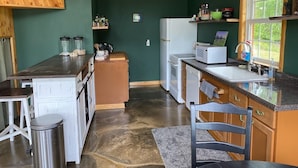 Une cuisine de taille réduite avec un plafond en bois, des murs verts et un plan de travail en granit.