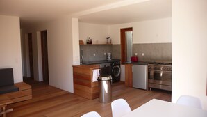 A compact kitchen with a washing machine, a coffee maker, and a stove. - New eco-certified house near the beach (Galéria)