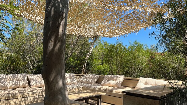 An outdoor seating area with a wooden table and benches, surrounded by trees and a pergola. - New eco-certified house near the beach (Galéria)