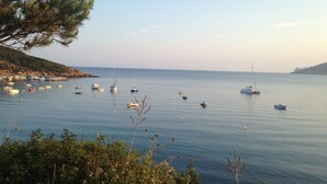 A coastal scene with boats anchored in calm waters, surrounded by greenery and hills. - New eco-certified house near the beach (Galéria)
