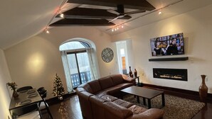 Ein Wohnzimmer mit einer Ledersofa, einem Couchtisch, einem Kamin und einem an der Wand montierten Fernseher.