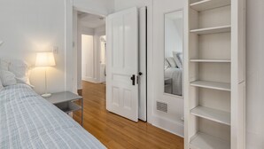 Un dormitorio con cama, mesita de noche, lámpara, armario y espejo.
