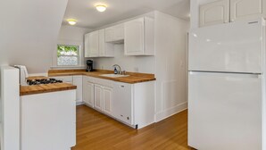Una cocina moderna con armarios blancos, encimera de madera, lavavajillas integrado y refrigerador blanco.