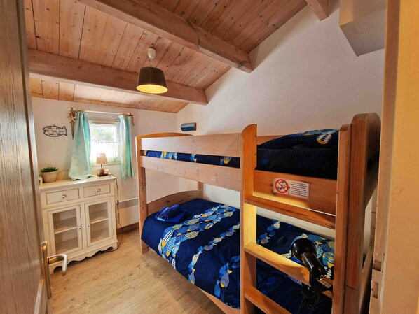 Une chambre avec un lit superposé, un plafond en bois et un bureau avec des tiroirs.