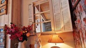 Un intérieur rustique avec des volets en bois, un vase de fleurs, une sculpture et une lampe de table.