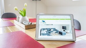 A tablet displaying a room layout with a sofa, coffee table, and TV.