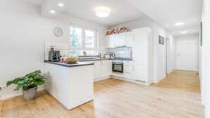 A modern kitchen with white cabinets, a central island, and a wooden floor.