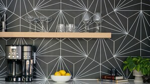 A kitchen with geometric backsplash, two wooden shelves with wine glasses, a coffee maker, a bowl of lemons, and a potted plant. - Gated Luxe Home with Rooftop, Bunk Room, & Parking  |  Sleeps 10 with King Suite, Queen Rooms & Custom Bunks, Chef’s Kitchen w/ Wine Fridge,  Rooftop Patio, Dog Friendly, Dedicated Parking, Mins from Downtown and Broadway, 24 Hour Hospitality (Nashville)